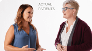 Two women talking to each other in front of a white background.