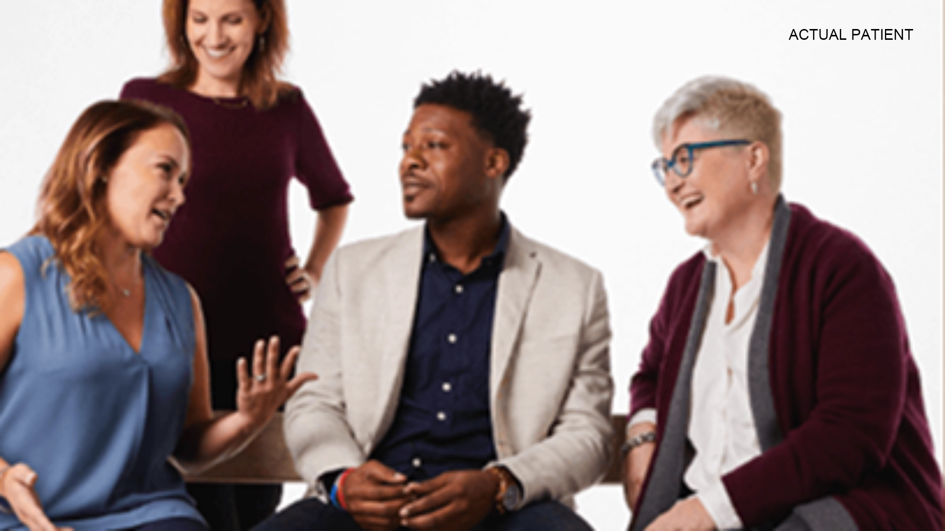 A group of four people having a conversation in front of a white background.