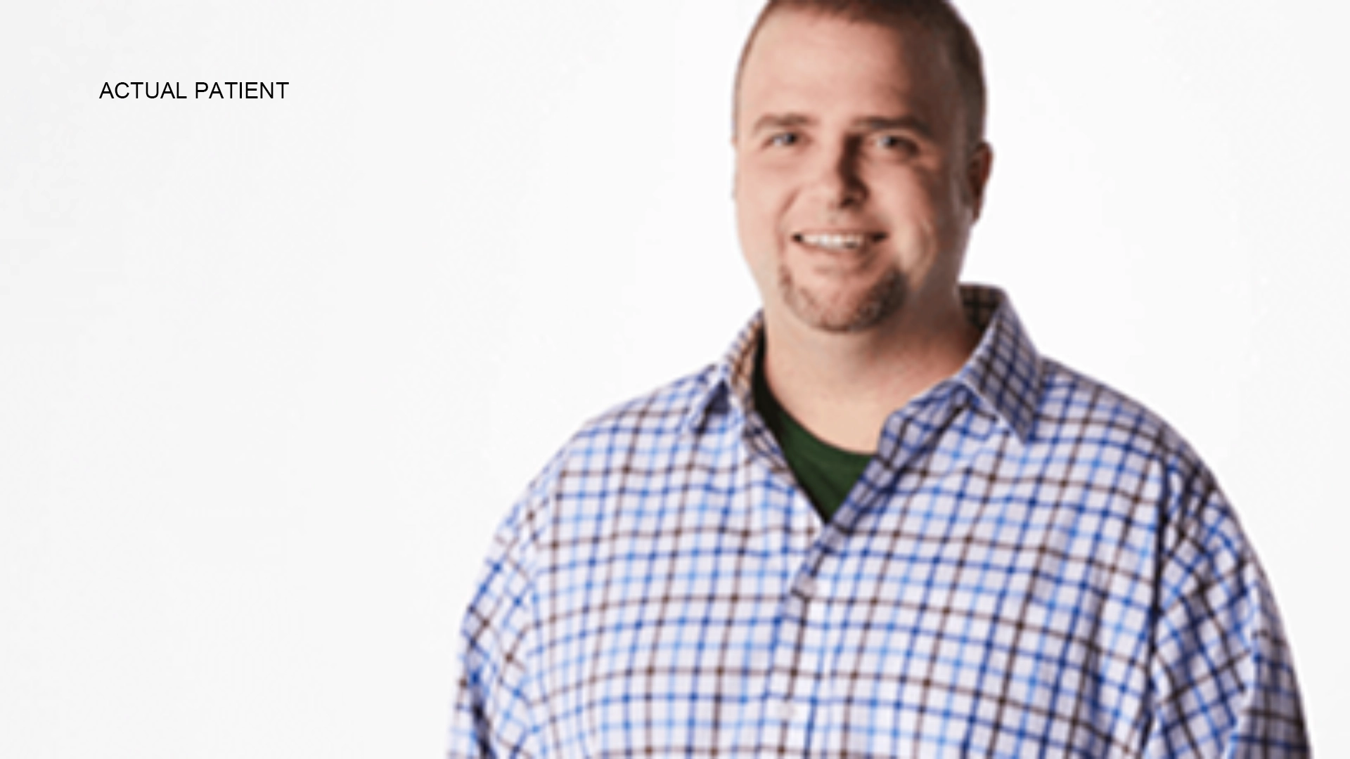 A bearded man wearing a checked shirt in front of a white background.