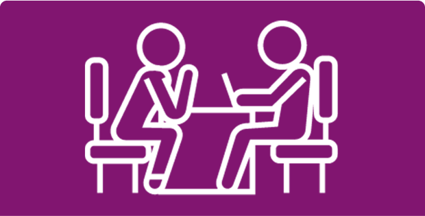 Icon of two people sitting at a table, one using a laptop on purple background.