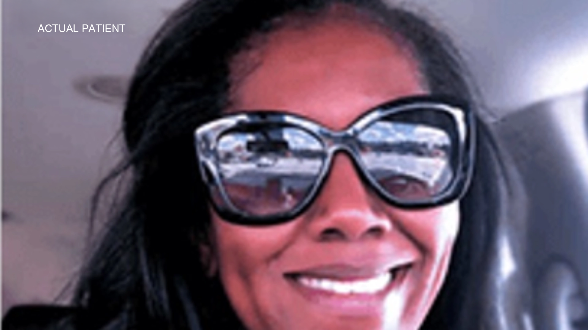 A smiling woman wearing oversized sunglasses inside a car.