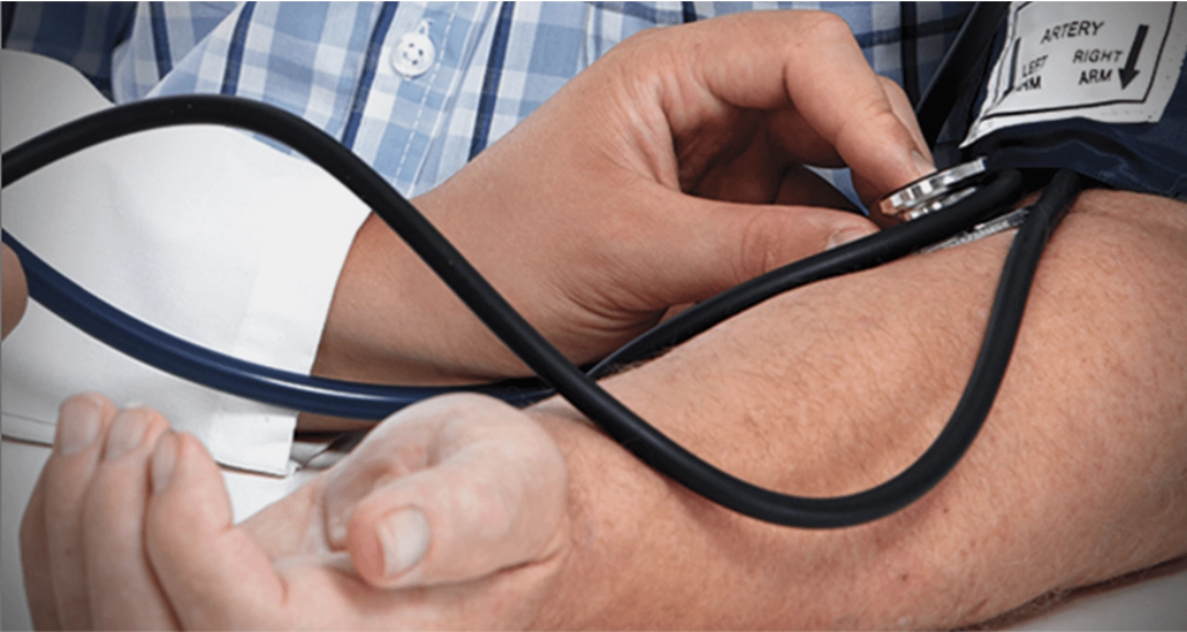 A person is checking another's blood pressure using a sphygmomanometer and stethoscope.