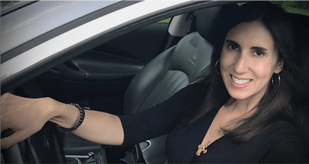 A woman wearing a black top is sitting in the driver's seat of a car.