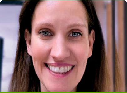 A woman with brown hair is smiling with a blurred background.